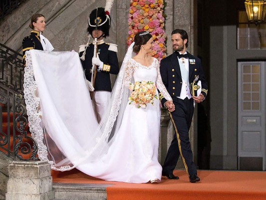 Sofia Hellqvist. La emoción era incontenible para la radiante novia, que el 13 de junio de 2015 llegó a la capilla del Palacio Real de Estocolmo para su enlace con el príncipe Carlos Felipe de Suecia. La novia llevaba un precioso vestido en crepé de seda y aplicaciones bordadas a mano de la diseñadora sueca Ida Sjöstedt con manga larga y escote en pico ceñido en la parte superior. Como es costumbre de la Familia Real Sueca, la novia llevaba un ramo de mirto en su bouquet compuesto además por rosas. Un beauty look natural con un elegante moño bajo coronado con una tiara regalo de los reyes de Suecia y aretes en forma de lágrimas complementaron el look nupcial.