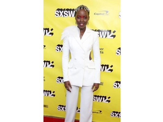 Lupita no para de sorprendernos. Aquí la podemos ver luciendo un suit completamente blanco, con una acentuación -y una sexy abertura- en la cintura. Lo extravagante, su peinado el cual tenía una clase de ganchos por toda su cabeza.