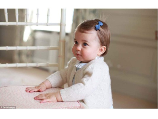 En esta imagen la princesa Charlotte, quien lleva un listón azul en su cabello, se apoya contra una silla.