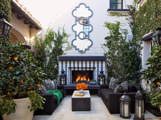 Acogedora y refrescante, la terraza gira en torno a la chimenea diseñada por Martyn Lawrence Bullard y un espejo XL que refleja el maravilloso entorno