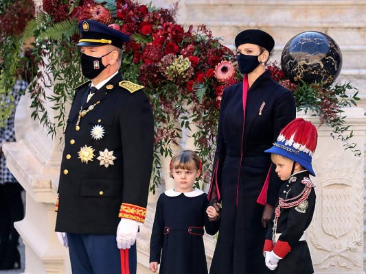 El príncipe Alberto, quien lució su traje militar, con su esposa Charlene, vestida con un coat dress en azul navy con un sutil lining en fucsia; y sus hijos Gabriella y Jacques (Photo by Valery HACHE / POOL / AFP)