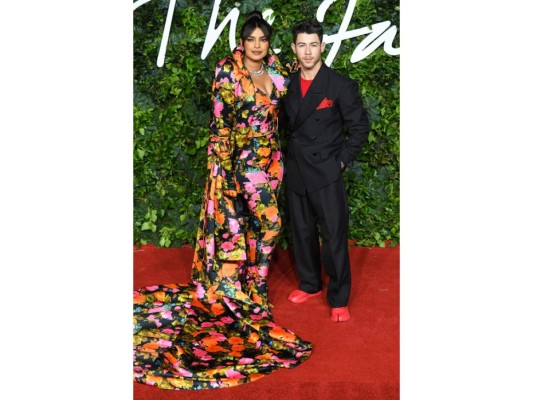 Nick Jonas y Priyanka. Para los Fashion Awards 2021, Priyanka lució un conjunto de vestido con abrigo largo de Richard Quinn mientras que su esposo Nick Jonas portó un elegante traje negro de Maison Margiela que combinó con zapatos rojos.