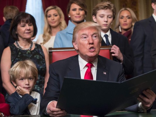 Donald Trump firma sus nombramientos de gabinete mientras su nieto, Joseph Frederick mira a la cámara