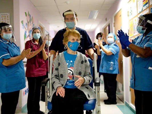 Margaret Keenan es aplaudida por el staff médico del University Hospital en Coventry luego de ser la primera persona en recibir la vacuna Pfizer-BioNtech Covid-19 en Inglaterra (Photo by Jacob King / POOL / AFP)