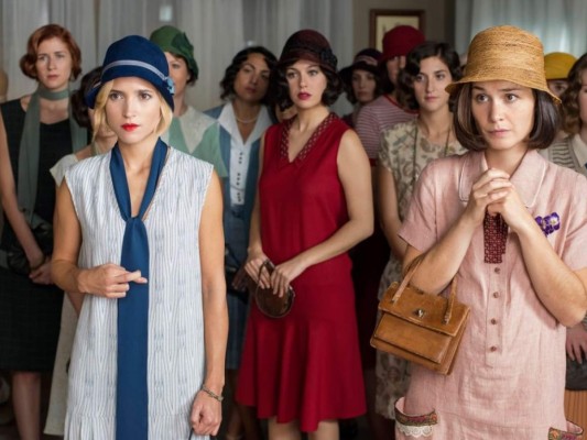 Las Chicas del Cable<br/>Esta es sin duda fascinante, no solo por su trama si no por el increíble vestuario que recrea de manera impresionante la dorada década de los 20´ y la innegable belleza de sus ''flappers''. Las protagonistas de la serie son working girls y llevan outfits cómodos, frescos y holgados para el día a día. Vemos siluetas rectilíneas, tejidos sedosos, satinados, gasas, detalles hechos a mano, blusas de cuello en v con lazos, y para el lujo y ostentación que representa la noche vemos encajes, pedrerías, pieles y todo tipo de bordados brillantes. En cuanto a accesorios y belleza vemos guantes cortos y sombreros cloche que combinaban a la perfección con los cortes bob que se ajustaban a la cabeza y acentuaban un maquillaje muy recargado.<br/>