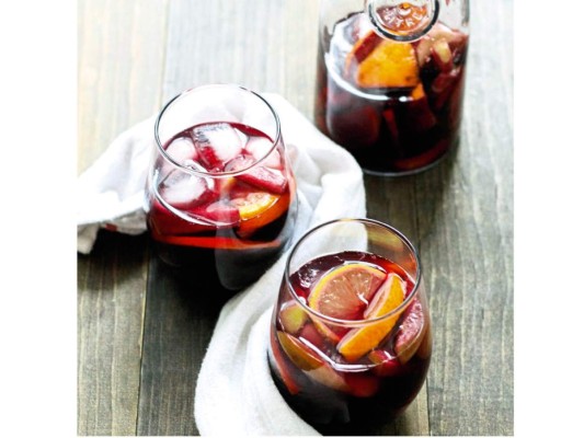 Sangría con melocotones<br/>Ingredientes. 1 cucharada de azúcar. 1 cucharada de agua. 1 taza de melocotones cortados en rodajas. 1/2 taza de naranjas en gajos o rodajas. 1/2 taza de zumo de naranja fresco. 1 botella de vino blanco. 1 onza de triple seco. 1 onza de vodka con sabor a naranja. Soda al gusto<br/><br/>Preparación. Coloca el azúcar y el agua en una cacerola, lleva al fuego y crea un sirope simple. Deja enfriar. Añade las frutas cortadas en rodajas en una jarra. Luego, por este orden el zumo de naranja, el vino, el triple seco y el vodka. Deja reposar en la nevera al menos dos horas. Añade el sirope antes de servir.<br/>