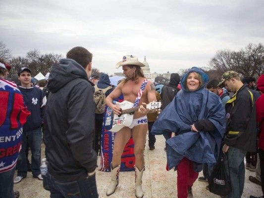 Un vaquero vestido con ropa interior toca la guitarra mientras la gente se reúne en el National Mall antes de la inauguración presidencial