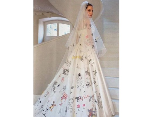 El vestido de Jolie está firmado por el creador de Atelier Versace , Luigi Massi. Por delante es sencillo, de seda blanca y con tirantes, pero su principal característica está detrás: tanto la parte baja del velo como la espalda y la cola del vestido están pintadas con dibujos de sus hijos.