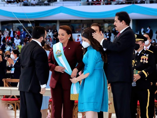 Irene Melara ayuda a su abuela a colocarse la banda color turquesa