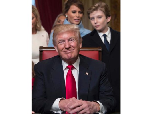 Donald Trump, vestido de suit azul oscuro, corbata roja y lujosas mancuernillas de diamantes, sonríe rodeado de su familia en el Salón del Presidente en el Senado