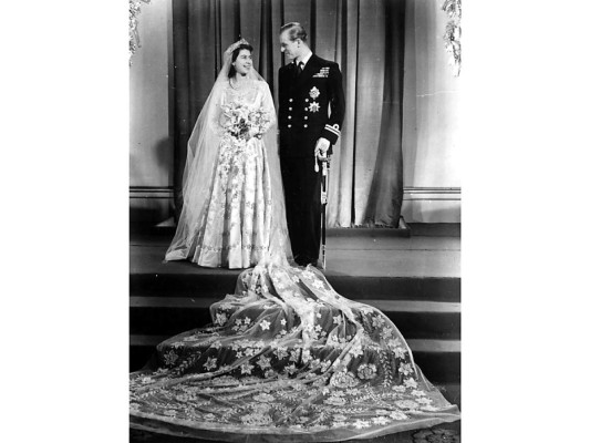 Isabel II de Inglaterra. Después de un largo noviazgo de 8 años, Isabel II desfiló hacia el altar el 20 de noviembre de 1946 para convertirse en la esposa Felipe de Edimburgo. La heredera a la corona inglesa, de apenas 21 años, lucía un vestido confeccionado en satín de duquesa de marfil y decorado con 10 mil perlas blancas, hilo de plata y bordado de tul. El diseño se complementó con una cola de 15 pies, que estaba atada en los hombros, y un velo de tul de seda sostenido por una tiara prestada a la princesa por su madre. Norman Harnell fue el creador de este memorable vestido cuya cola de cuatro metros y medio de largo incluía varias estrellas parecidas al cuadro de Botticelli: La Primavera.<br/>