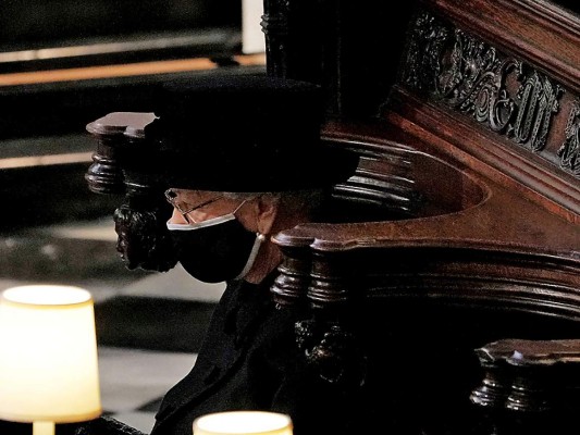 Vestida de riguroso negro y con un discreto toque de brillo del broche Richmond de la reina Mary, la monarca Isabel II ocupó un solitario puesto en el coro de la capilla (Photo by Yui Mok / POOL / AFP)