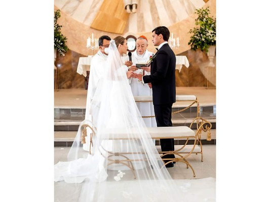 Los enamorados realizan el intercambio de sortijas mientras el cardenal Oscar Andrés Rodríguez bendice su unión.