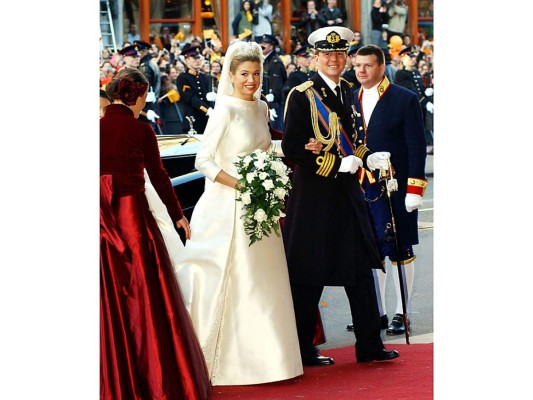 Máxima de Holanda. Ese 2 de febrero de 2002, centenares de invitados aguardaban pacientes el momento que la argentina Máxima Zorreguieta apareciera junto a su prometido, Guillermo de Holanda, para protagonizar una boda memorable. La novia, que tal como dicta la tradición holandesa, desfiló hacia el altar del brazo de su novio, lucía radiante en un hermoso vestido blanco marfil diseñado por Valentino. Sencillo pero imponente, el vestido de manga larga ajustada, cuello redondo, cuerpo liso con dos discretas aplicaciones de encaje y una larga cola de cinco metros de largo, era perfecto. El velo, confeccionado en tul de seda con detalles florales hechos a mano, era sujetado por una brillante tiara de estrellas, la misma que lució la reina Beatriz en su boda con el príncipe Claus hace más de 50 años. Máxima llevaba unos pendientes lagos de diamantes con una pulsera a juego. Su bouquet lo formaban rosas, gardenias y lirios blancos.