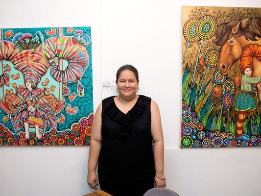 La pintora Leticia Banegas junto a sus obras llenas de color y creatividad.