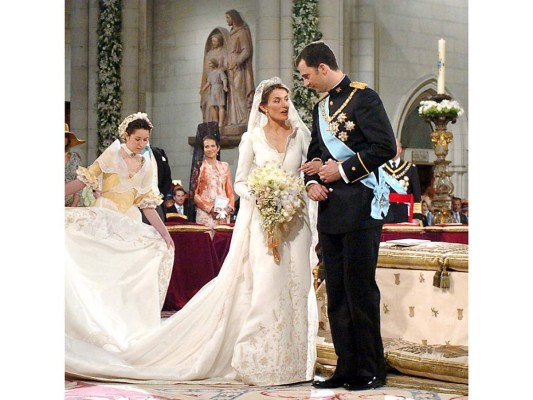 Letizia Ortiz. La lluvia caía sobre la catedral de Almudena en Madrid ese 22 de mayo de 2004 cuando Letizia Ortiz se convirtió en la esposa de Felipe de España. La periodista eligió como diseñador de su ajuar a Manuel Pertegaz, quien le confeccionó un vestido blanco de seda natural tramada con hilos de plata fina, corte princesa, manga larga, ceñido al talle, escote en pico con cuello en forma de corola, falda amplia y cola de 4,5 metros bordada con motivos heráldicos. Letizia no podía lucir más espectacular con ese diseño que complementó con la misma tiara estilo imperio, en platino y diamantes, que llevó su suegra, la reina Sofía, el día de su boda. El velo nupcial, de seda natural en blanco marfil, medía tres metros de largo y en el destacaban guirnaldas bordadas a mano, que mezclaban la flor de lis y la espiga. Los accesorios incluían unos pendientes de platino con diamantes, regalo de los reyes de España. El ramo incluía rosas rosas isabelinas, iris y lirios, unas flores que históricamente han estado ligadas a la dinastía de los Borbones.