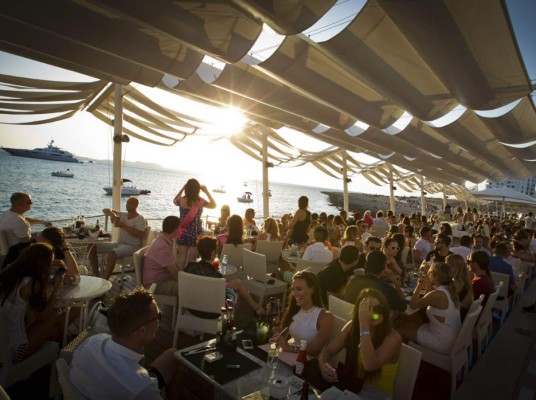 Te invitamos a disfrutar de la puesta del sol con una deliciosa Hierba Ibicenca o con vino local desde la terraza de Café del Mar en San Antonio de Portmany, en la isla de Ibiza.