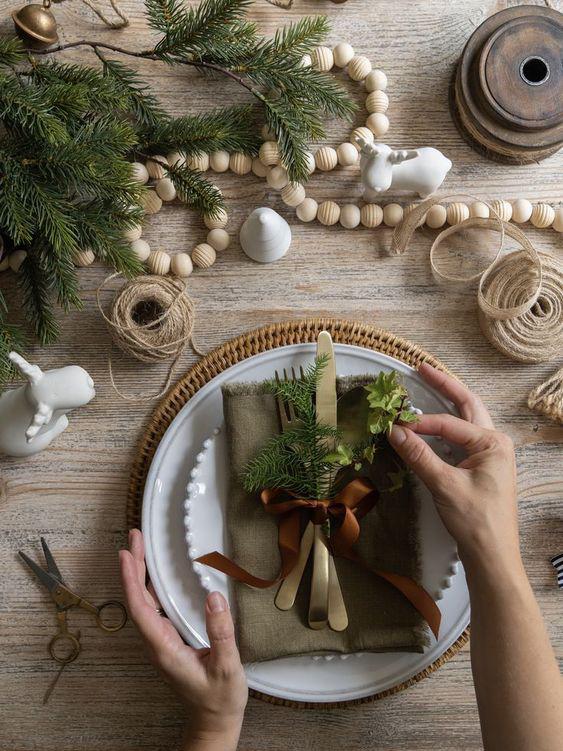 Sencilla y rústica mesa navideña. El uso de colores neutros y la vegetación combinados crean una mesa elegante y totalmente adecuada para el día de Navidad