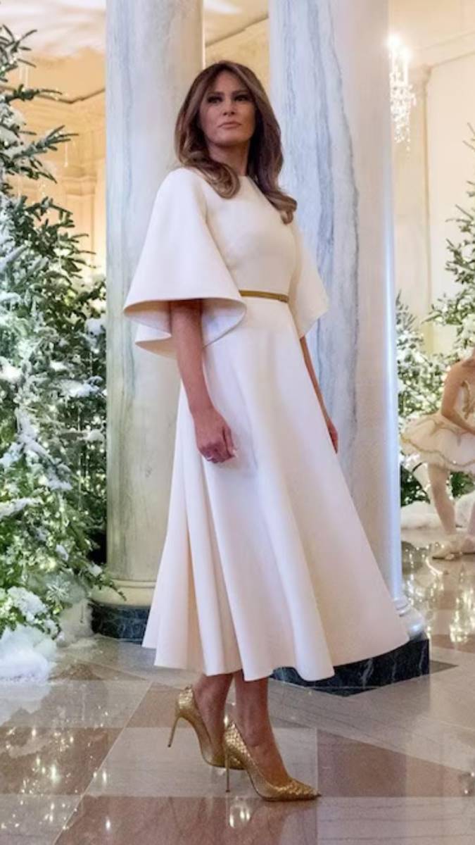 En sus primeras navidades en la Casa Blanca, Melania Trump deslumbró con un vestido blanco de <b>Dior</b> para presentar la decoración navideña, diseño que también había llevado en azul marino en su visita a Japón semanas antes. La elegante silueta del vestido, comparada por muchos con la de un “ángel”, rápidamente se convirtió en uno de sus favoritos y en un símbolo de su estilo refinado como primera dama.
