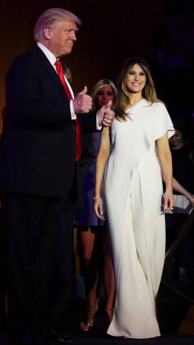 En la noche de su primera victoria electoral en 2016, Melania Trump captó la atención con un elegante mono blanco de <b>Ralph Lauren</b>. Este look, de corte impecable y líneas limpias, no solo resaltó su figura, sino que fue percibido como un símbolo de paz y esperanza, características que el blanco suele evocar en momentos significativos. Su elección de un diseño tan minimalista y luminoso contrastó con la intensidad de la ocasión, reflejando una imagen poderosa y, a la vez, sofisticada, lo cual estableció desde el inicio su identidad visual como primera dama.