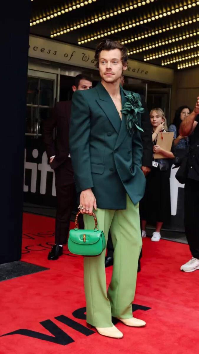 Con un blazer verde esmeralda cruzado y un par de pantalones verde lima, chaqueta adornada con un llamativo alfiler floral grande hecho con satén verde. Styles completó el look con un bolso con asa superior Gucci Bamboo 1947