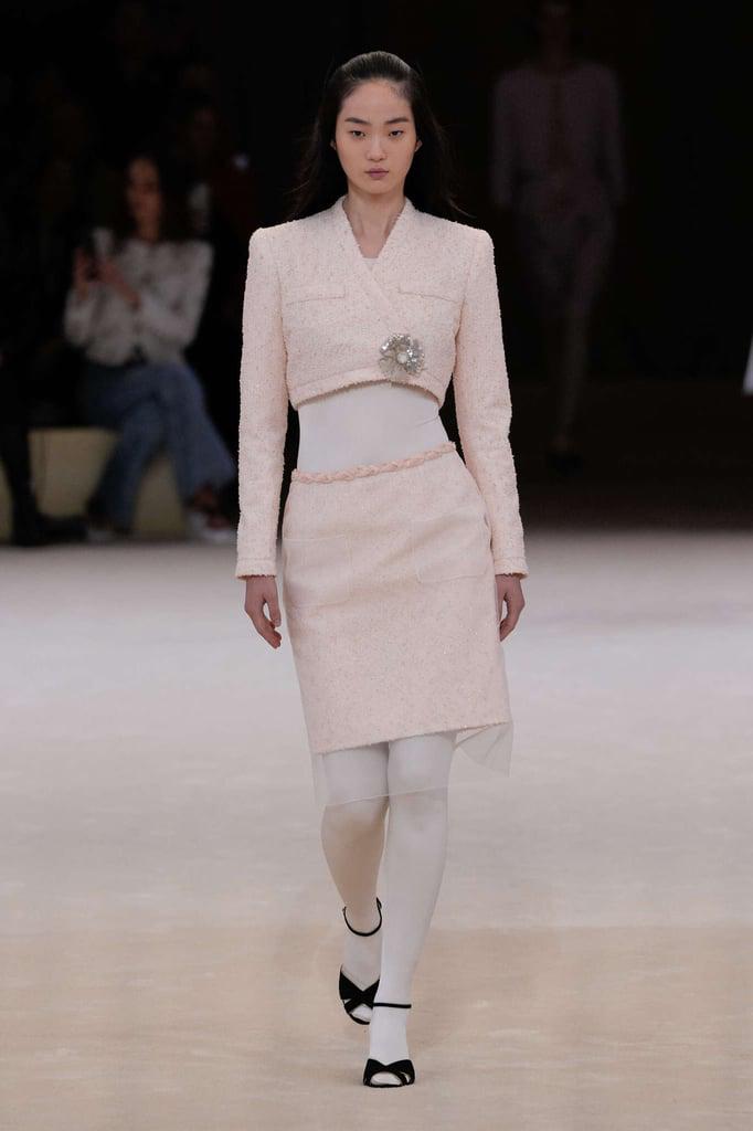 Las clásica chaqueta de Chanel se acortan y el tweed se combina con medias blancas, zapatos de tacón y claro un bellísimo broche.