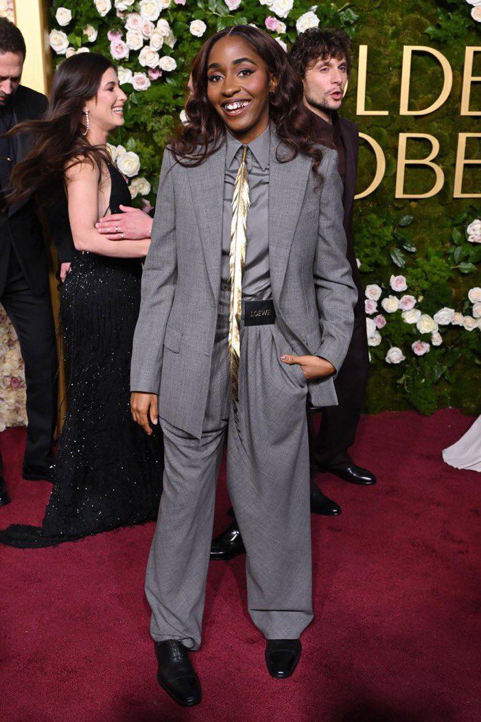 Ayo Edebiri destacó en los Golden Globes 2025 con un traje gris personalizado de Loewe, complementado con joyas de Mejuri.