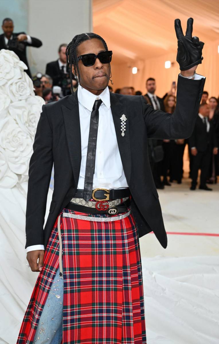 A$AP Rocky lució un diseño inspirado en Lagerfeld con un blazer negro y una camisa blanca abotonada con una corbata de cuero negro, además de una falda escocesa, firmado por Gucci.