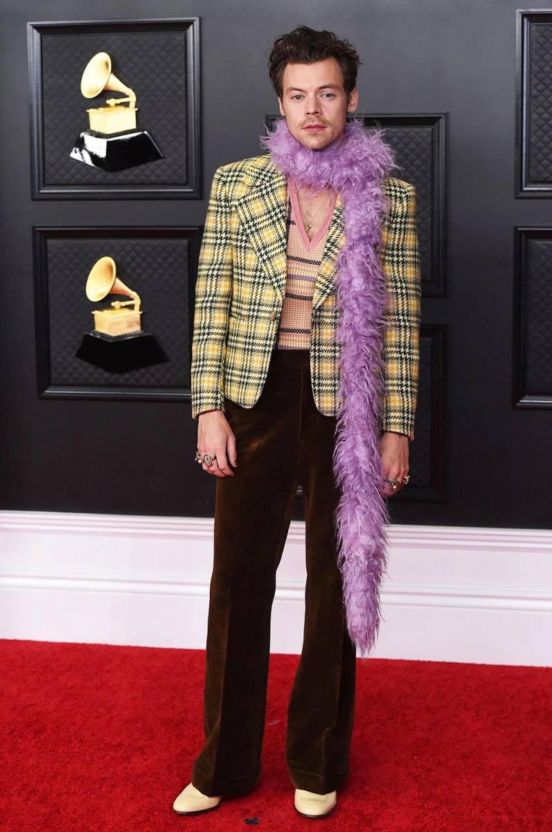 De chaqueta de cuadros escoceses con pantalones acampanados marrones, una camiseta sin mangas de punto y una fabulosa boa morada.