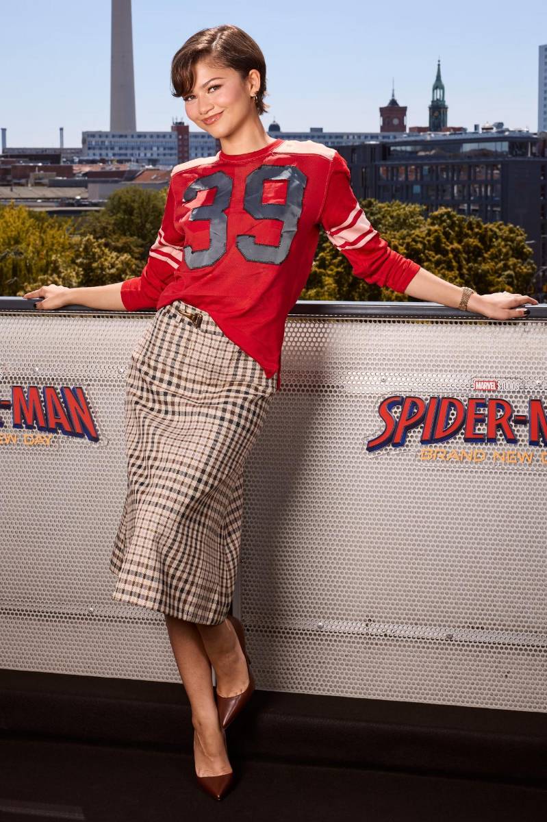 La estrella se inspiró en la moda deportiva para asistir a un fan event en Berlín, luciendo una camiseta roja al estilo jersey con una falda de cuadros absolutamente chic, siendo ambas prendas de la marca Coach. Sus tacones cafés de punta afilada combinaban con la midi skirt.
