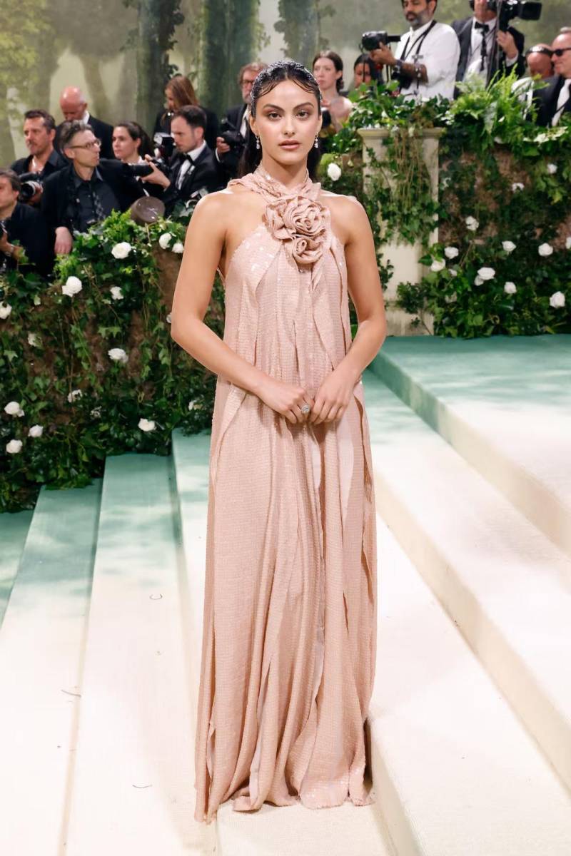Camila Mendes destacó con este vestido de cuello halter y flor de tela en color rosa palo, con volantes que dibujan su silueta diseñado por Joseph Altuzarra.