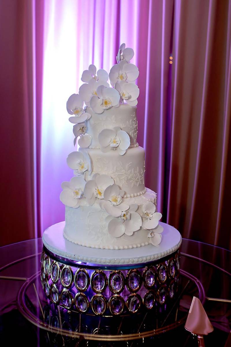 Pastel de boda de tres niveles con detalles de flores de azúcar y grabados.