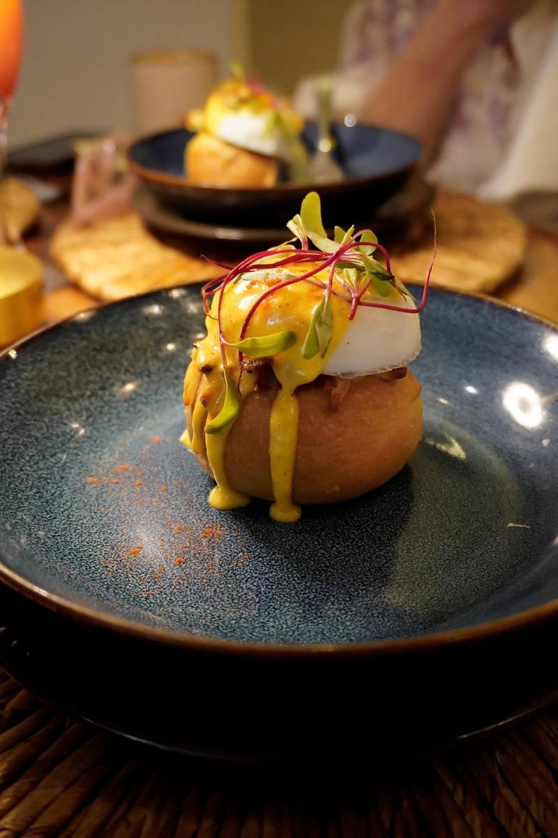 Huevos benedictinos con tocino, cubiertos con salsa holabndesa y queso mozzarella sobre pan de coco artesanal, parte del nuevo menú de desayunos diseñado por Nehemías Cárdenas, chef ejecutivo de Fusión