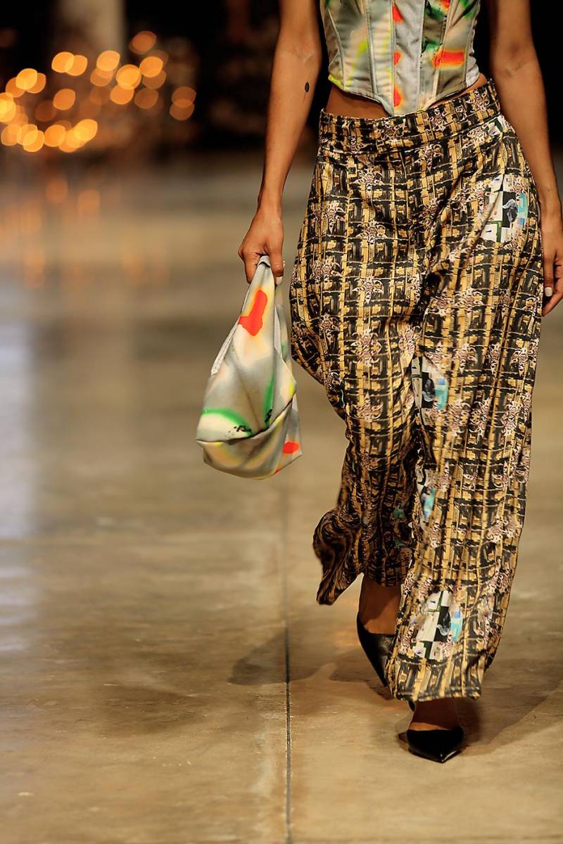 Pantalones con estampados coloridos junto a un corset metálico. La colección combina diferentes tipos de estampados. Además, la bolsa vibrante aporta un destello de color.
