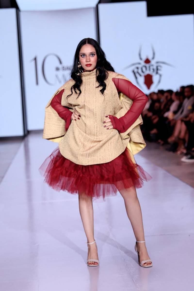 Conjunto de tres piezas: blusa de mesh rojo con capa de brocado dorado y cuello bote alto, combinada con una falda de tul rojo. Un look que equilibra volumen, textura y elegancia.