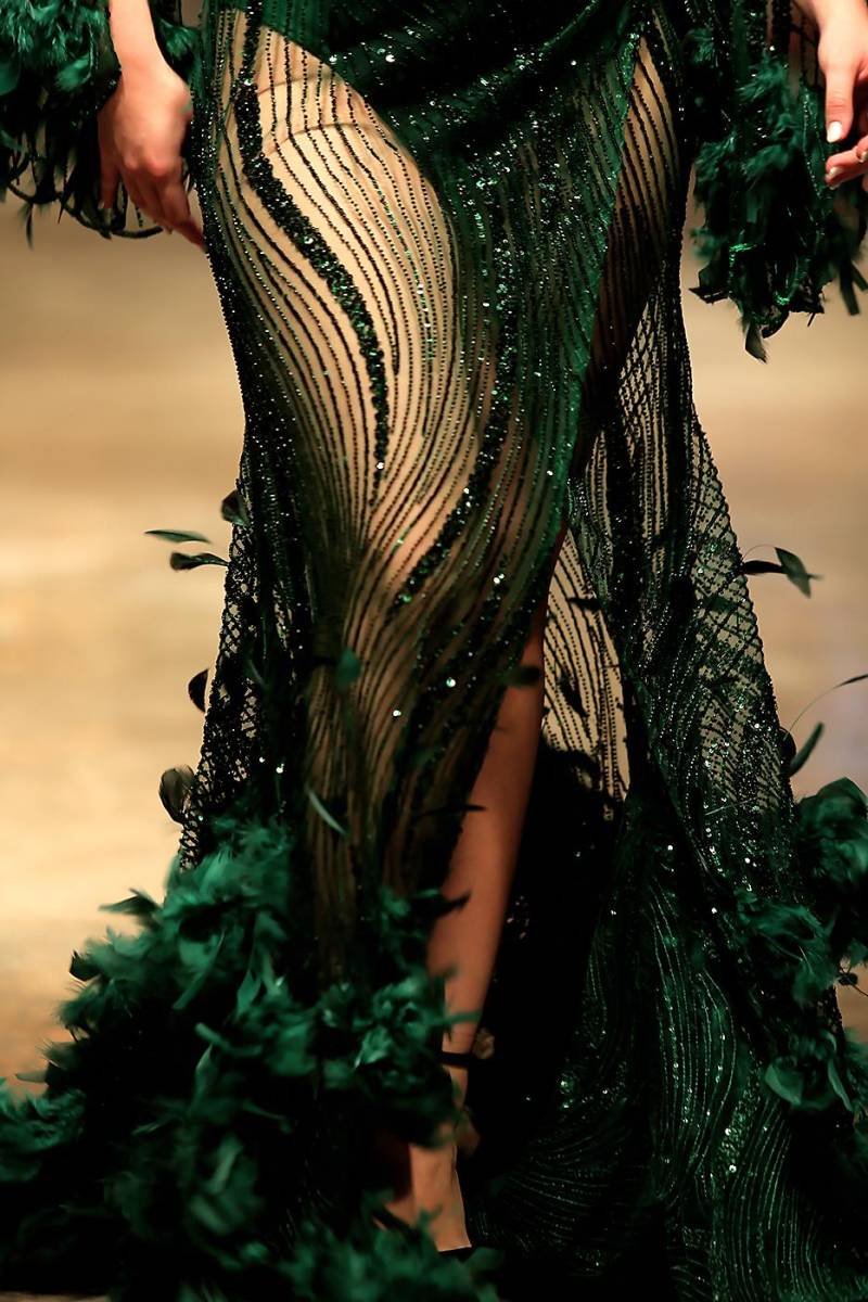 Sinuosos bordados de cristales y lentejuelas dan vida a este vestido con falda de abertura con aplicaciones de plumas de avestruz
