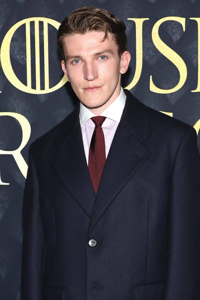 Ewan Mitchell portó un clásico traje con un toque de color con una corbata roja.