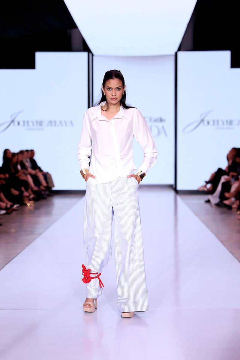 Camisa de botones con drapeado en el centro y línea de botones irregular de lino ferragamo blanco acompañado de pantalones anchos de algodón estampado de líneas.