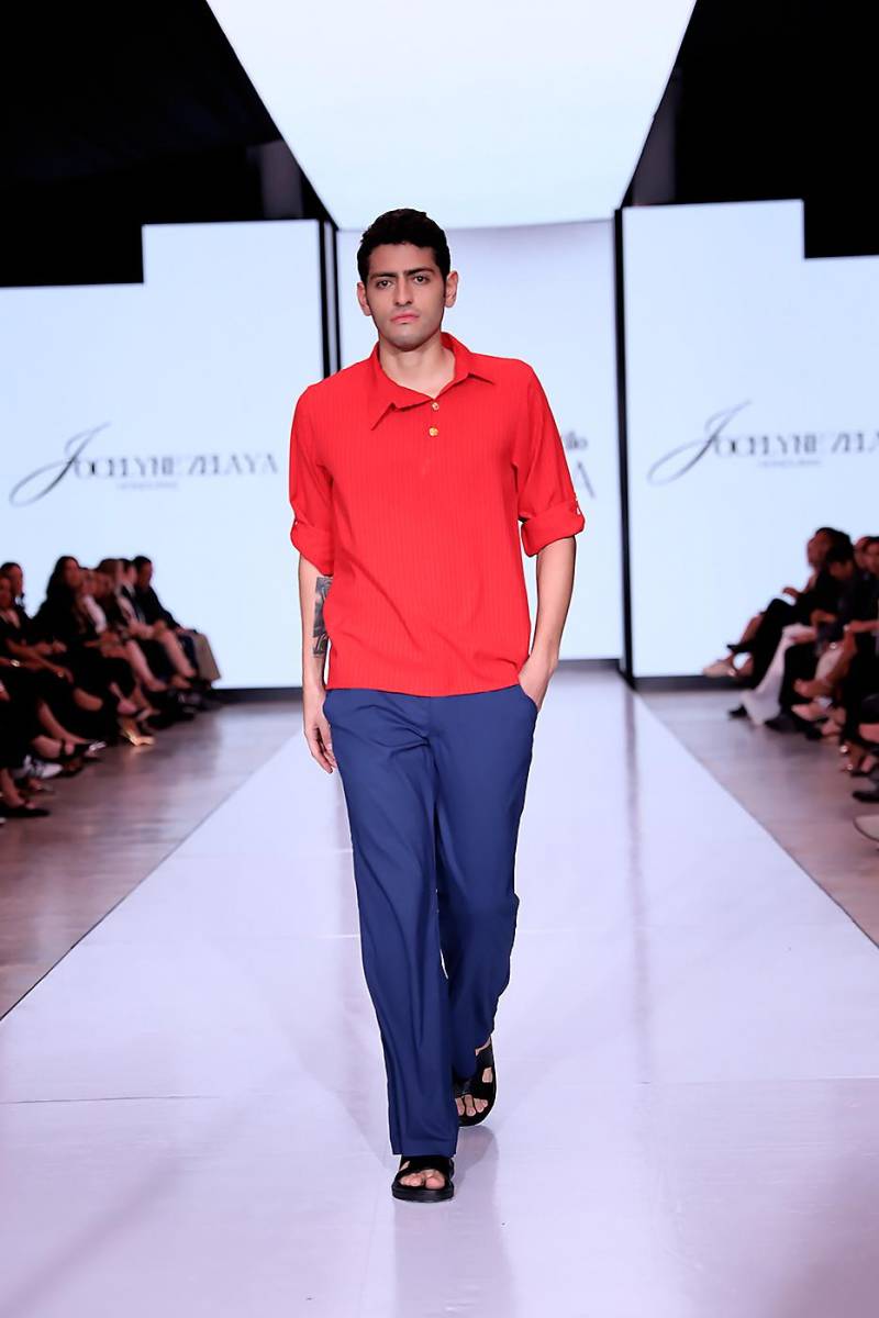 Camisa de botones con línea de botones tipo polo irregular, manga larga con amarre en los codos, acompañado de un pantalón de Casimir azul marino.