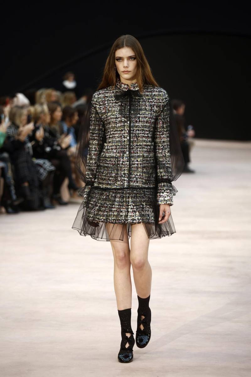 La delicadeza también interviene en forma de vaqueros de gasa, seda que parece tweed, un estampado de motivos de cintas flotando al viento y como una parka con capucha en organza negra adornada con lazos.