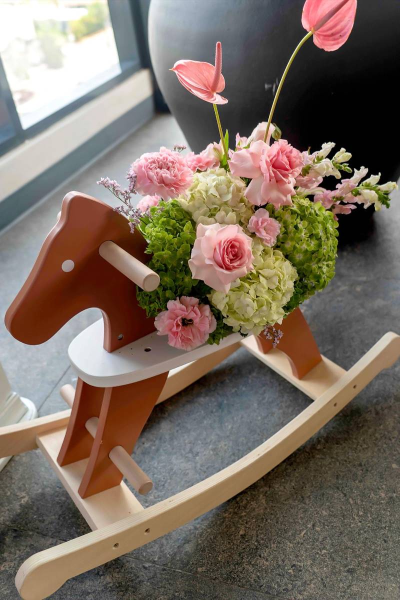 Caballo de madera adornado con rosas, hortensias, anturios y gladiolas