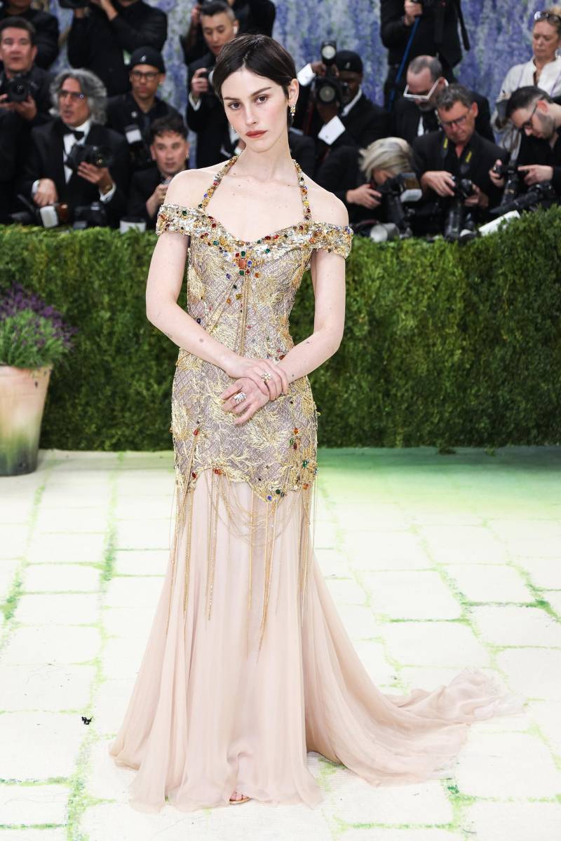 Gracie Abrams llegó a la Met Gala con un look que convirtió el arte en alta costura. La cantante apostó por un diseño dorado de Chanel inspirado en la estética ornamental de Gustav Klimt, evocando sus icónicas pinceladas doradas y texturas etéreas. La propuesta se completó con delicadas piezas de alta joyería de la maison, aretes colgantes y anillos en oro amarillo y diamantes, que aportaron un brillo sutil pero contundente.