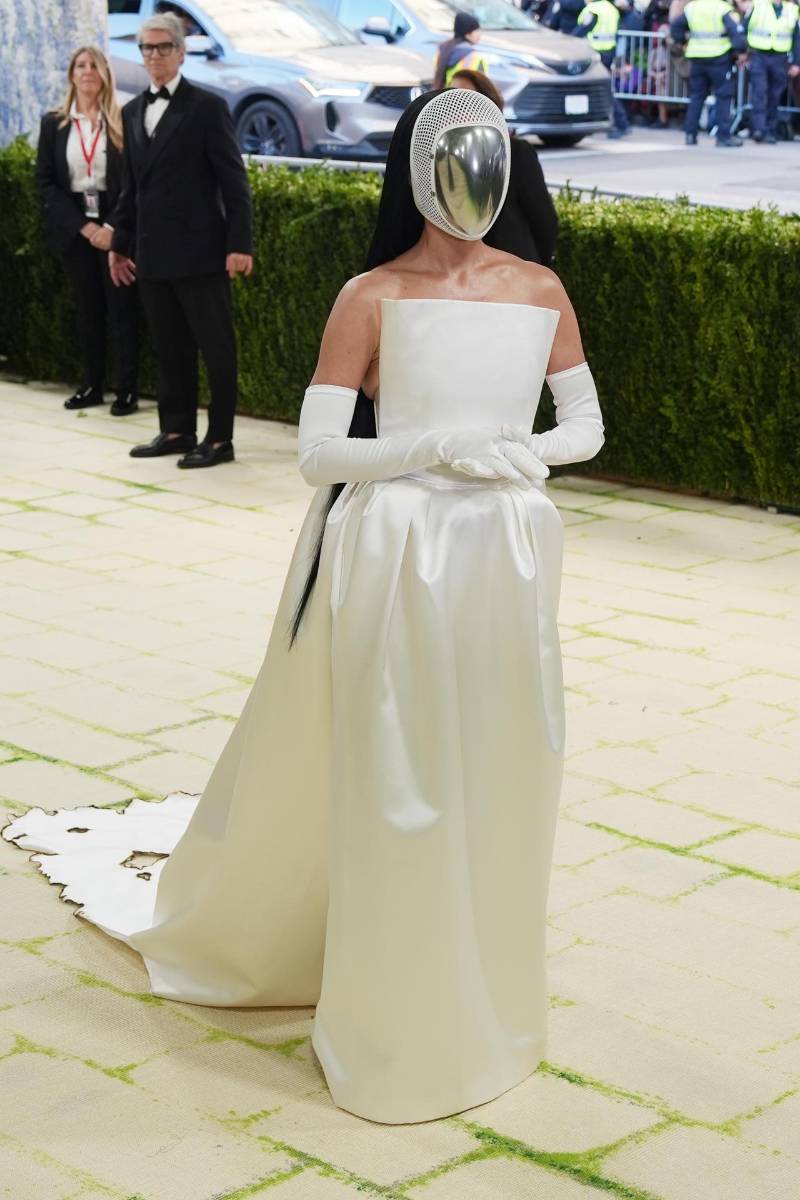  La cantante y actriz estadounidense Katy Perry llega a la gala en un total white look de Stella McCartney que partía de un <b>v</b>estido strapless con silueta estructurada, paneles translúcidos y una cola dramática, confeccionado en satén reutilizado, reafirmando también un guiño consciente hacia la sostenibilidad.