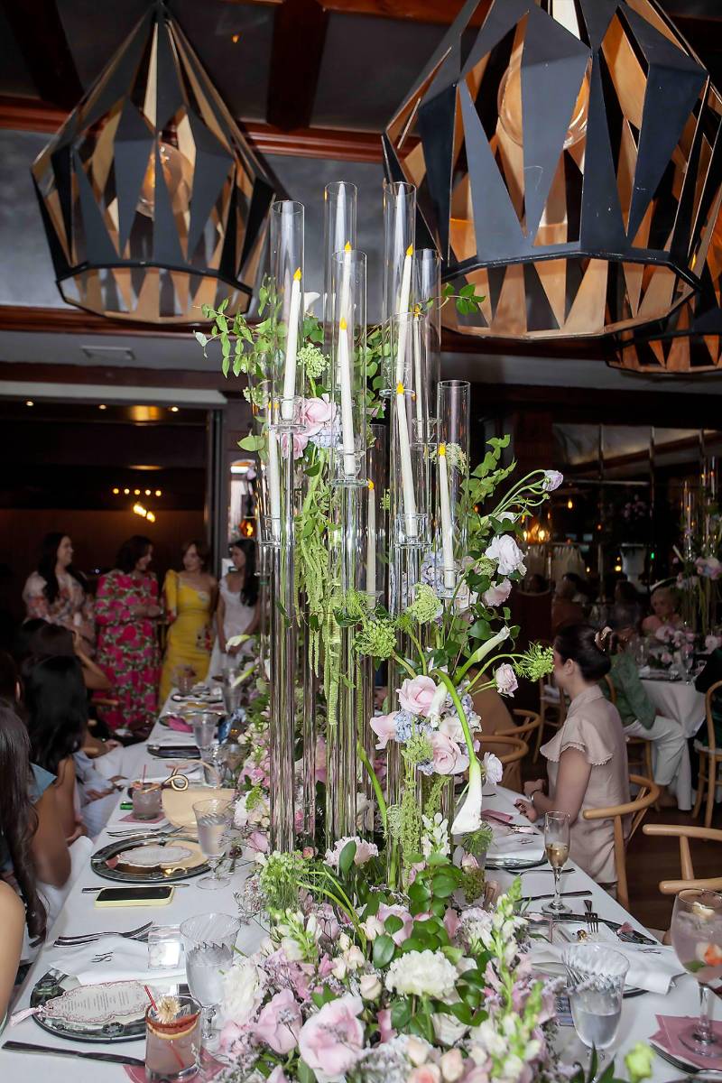 Arreglos altos con bases de vidrio y hermosos arreglos adornaron las mesas dispuestas para el festejo.
