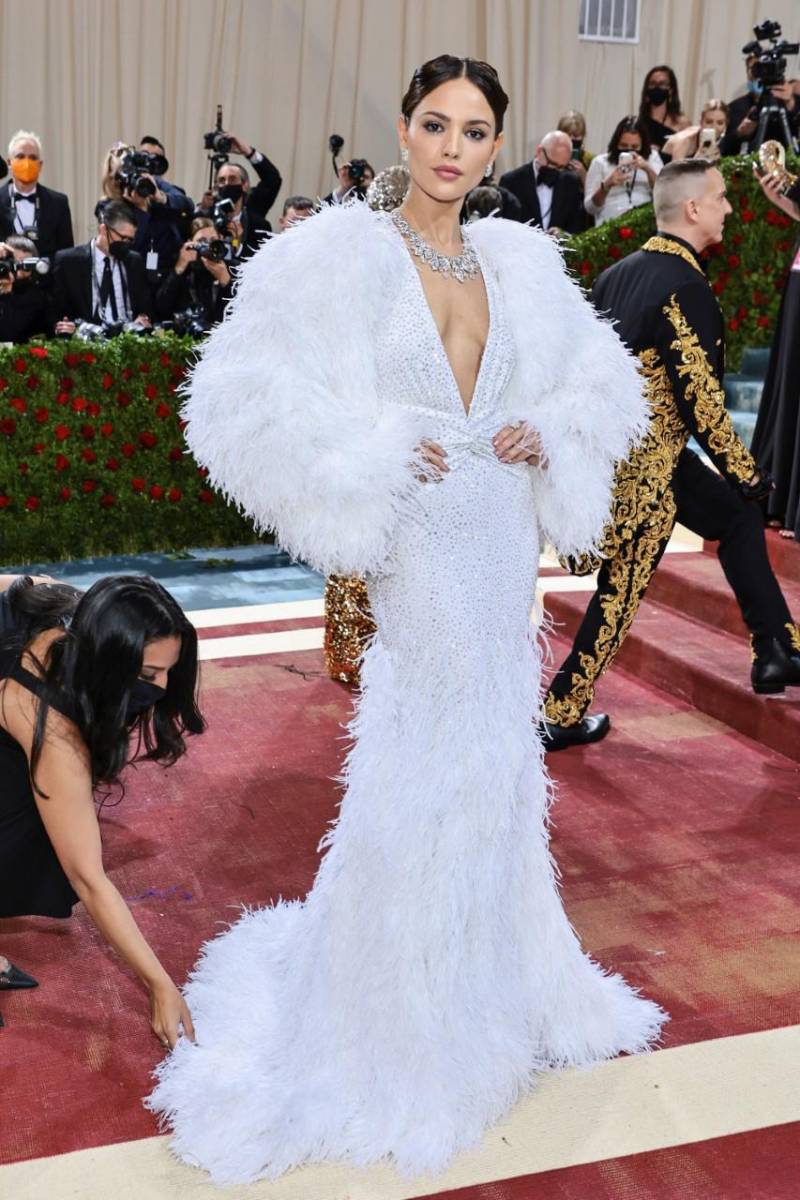 Eiza González en la Met Gala de 2022 lució un Michael Kors custom made que requirió más de 4, 700 horas de trabajo, el vestido corte de sirena tiene 28, 800 cristales y plumas de avestruz. Valorado en más de 35 mil dólares.