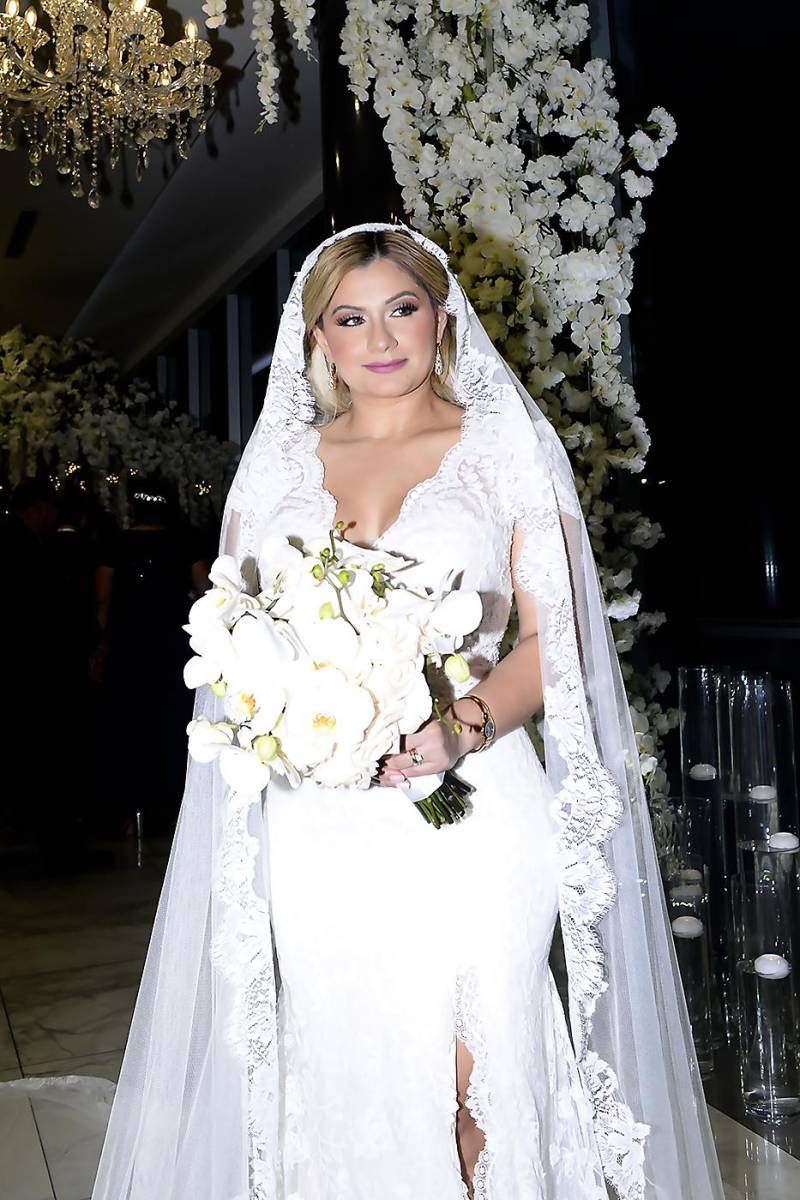  Para la ocasión la novia lució un delicado ajuar de la colección Negara de Rosa Clará: estilo sirena de encaje,escote profundo, manga corta, larga cola con un estilo romántico, un bouquet de orquídeas blancas y elementos personalizados