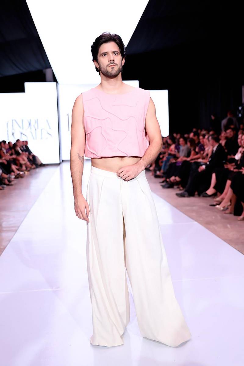 Cada pieza reflejo un equilibrio entre técnica artesanal, escotes innovadores y siluetas contemporáneas, celebrando la versatilidad y elegancia de la mujer moderna. Top masculino a la cintura en lino rosado con cierre zipper, combinado con pantalón ancho en lino beige, una interpretación contemporánea de la sastrería artesanal.