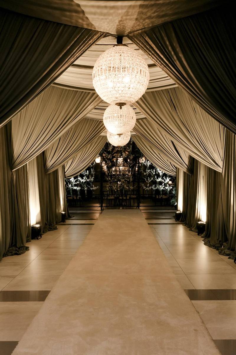 Lienzos de tela con lámparas fueron ubicadas en la entrada del salón como formando un túnel elegante donde también se instaló una alfombra.