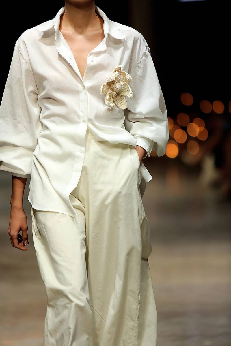Prendas frescas y ligeras, perfectas para disfrutar el verano. Una flor oversize tejida en crochet acentúa la naturalidad del lino en esta camisa de mangas abullonadas.