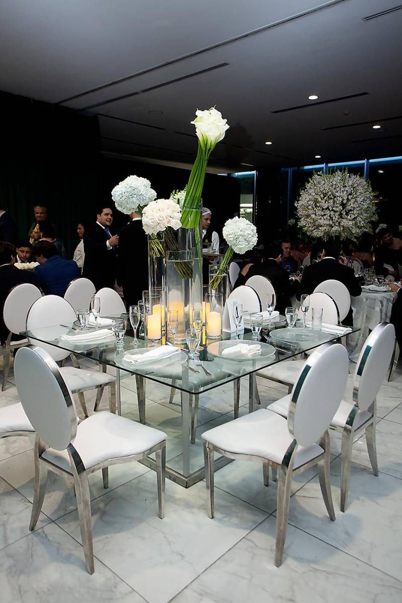 Mesa rectangular de vidrio con arreglos de bases altas con lirios Cala y hortensias con mesas Luis XV